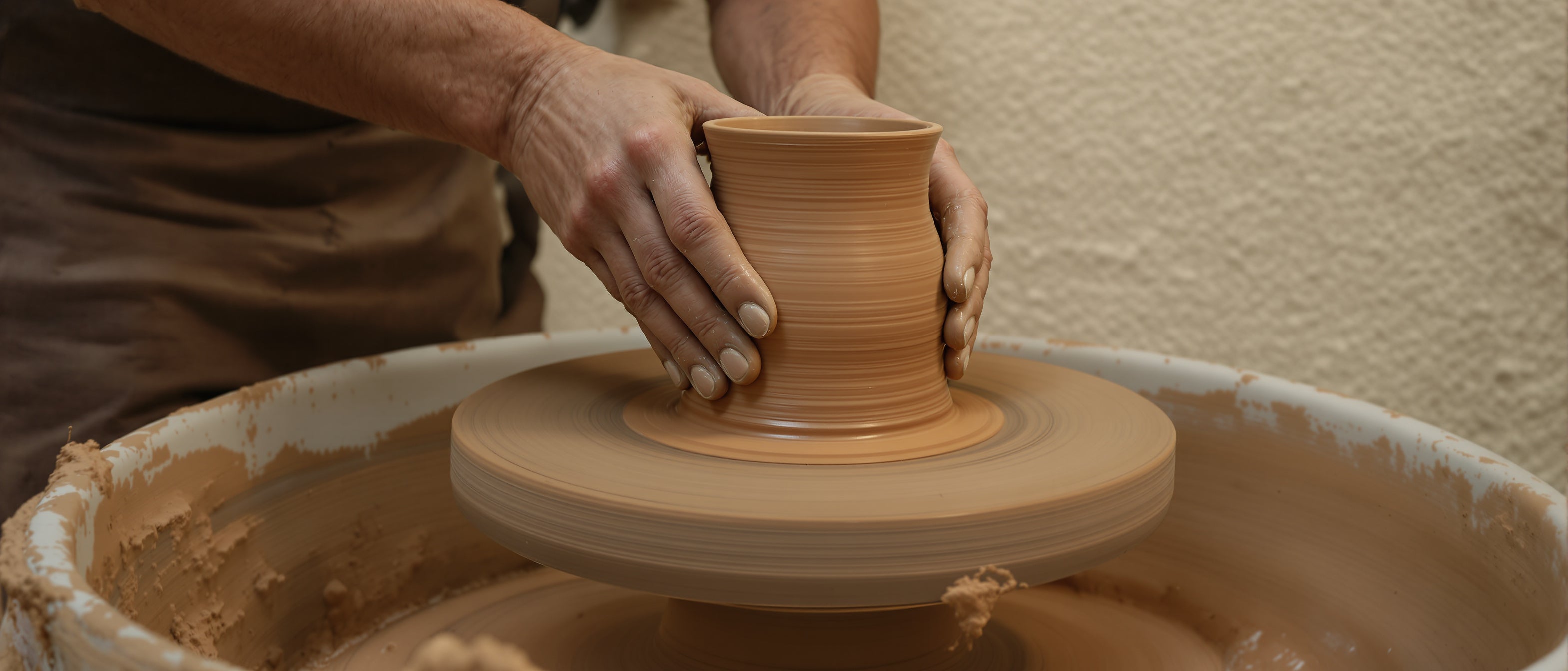 Taller cerámico Tiendalodama — manos modelando arcilla en torno de alfarero con luz mediterránea